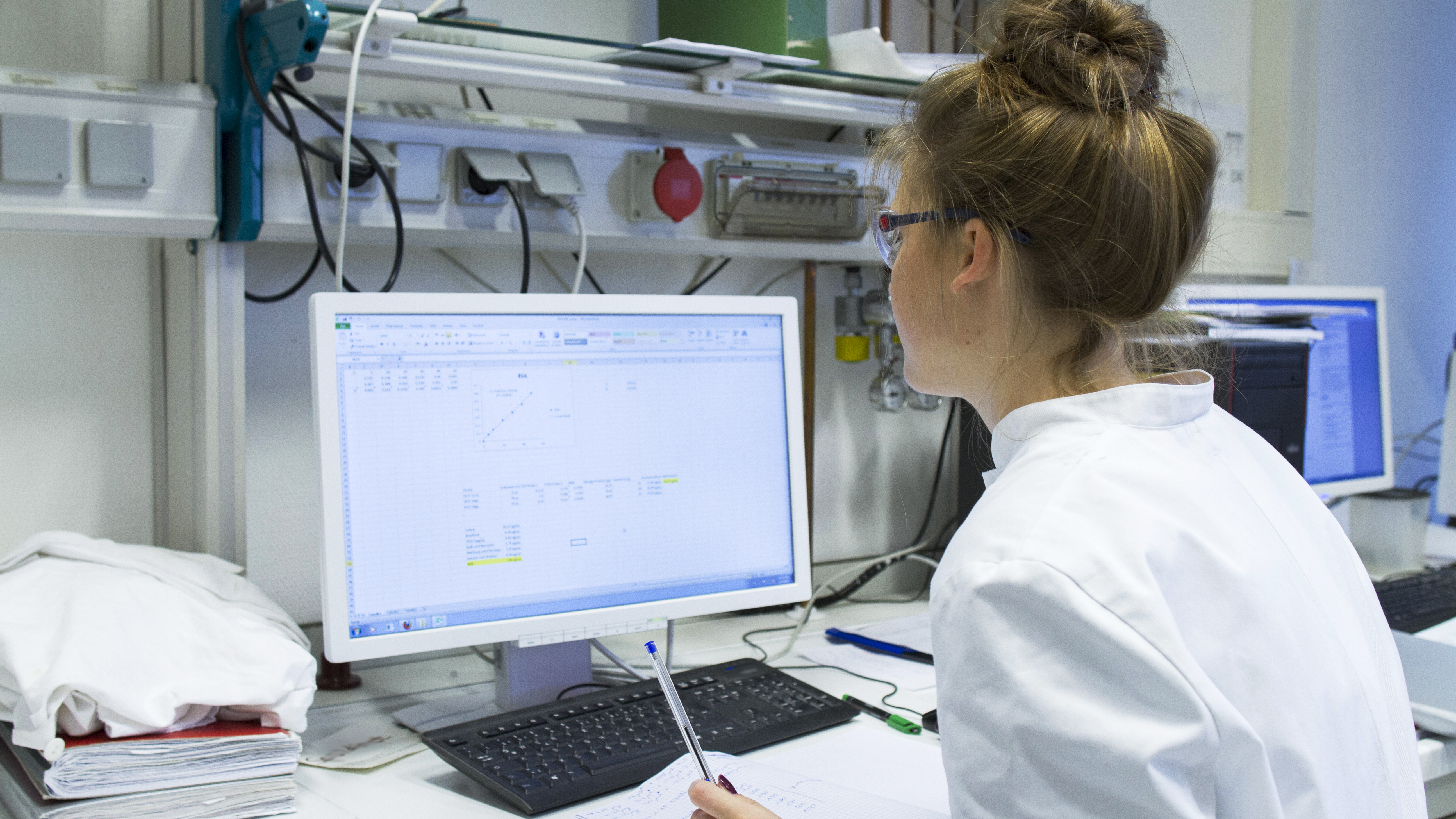 Laboratory technician with record working at computer