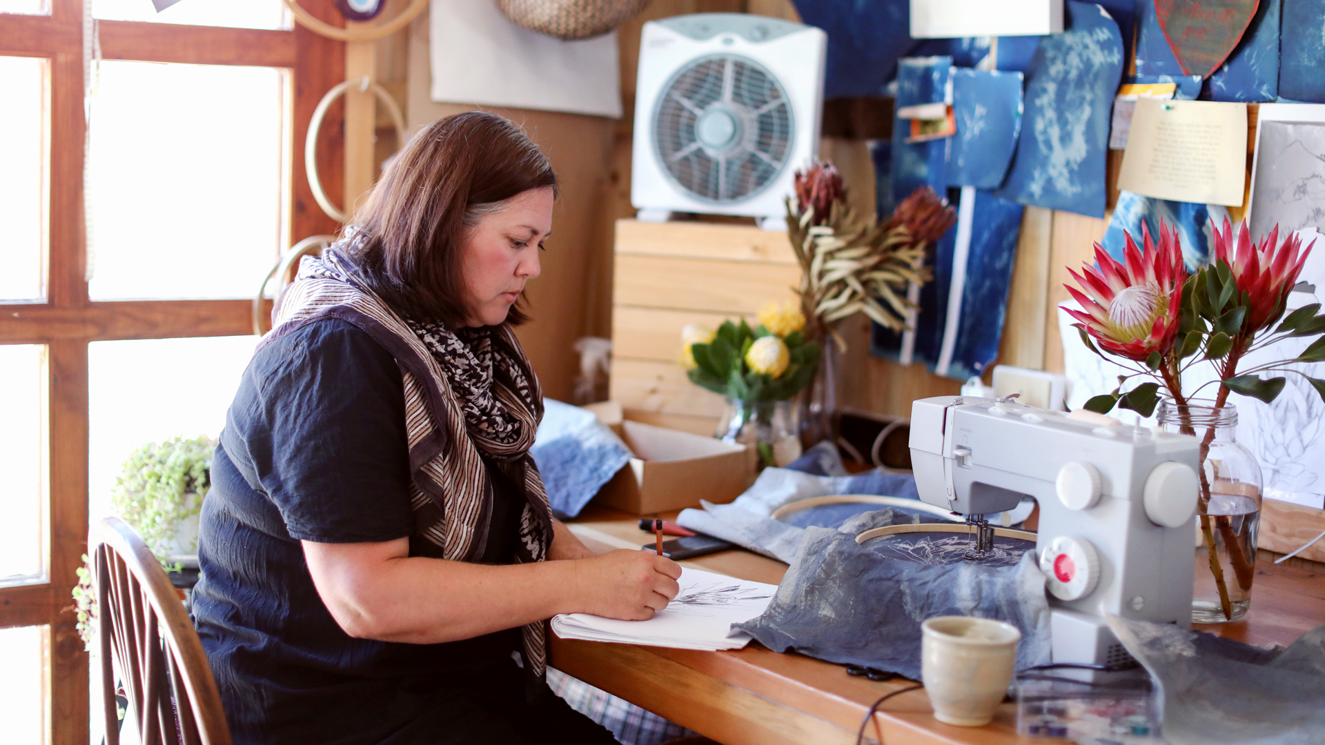 Photo of a woman working at desk with a sewing machine.