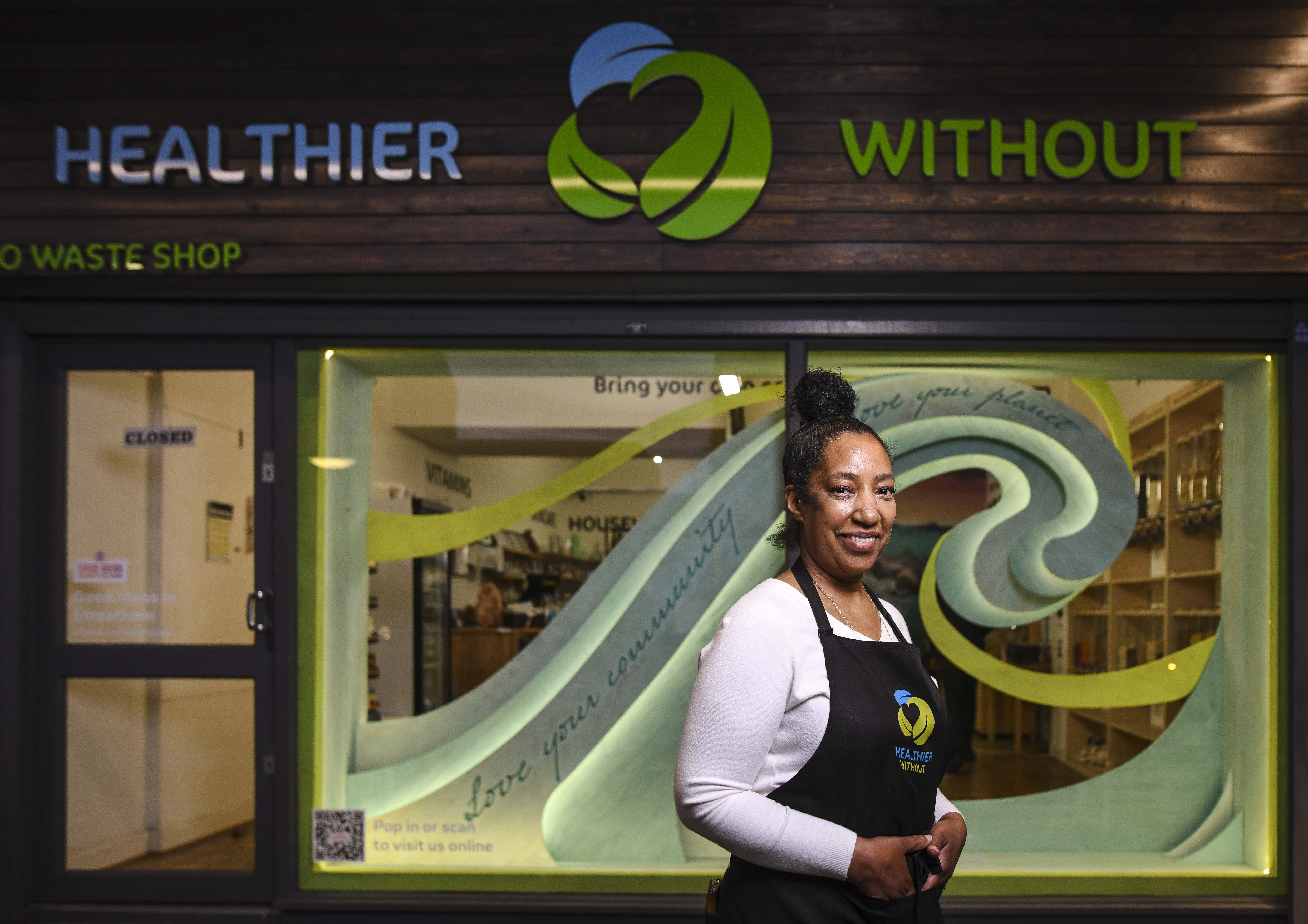 Female business owner standing in front of a shop window.