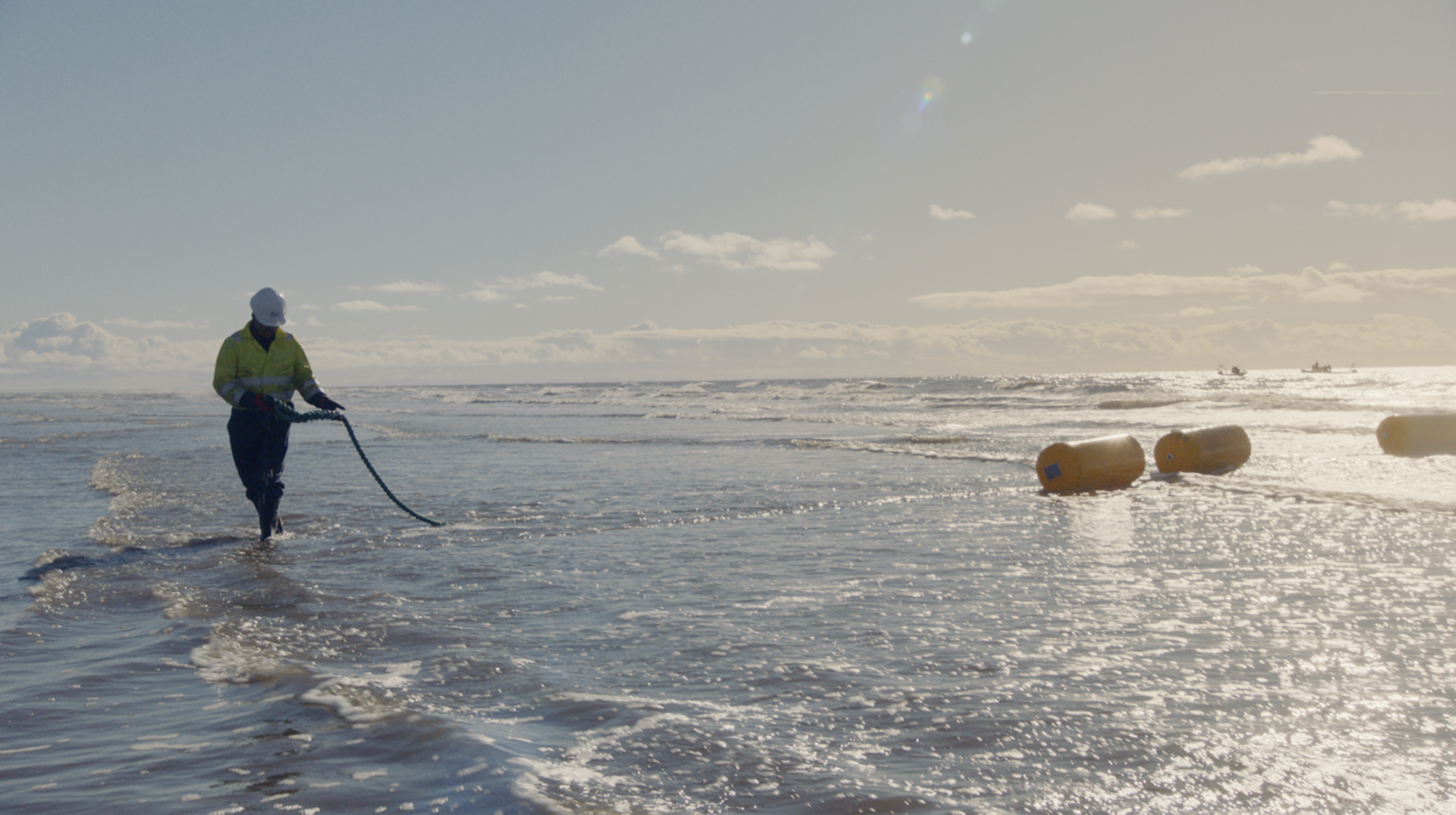 Person laying a cable in the sea.