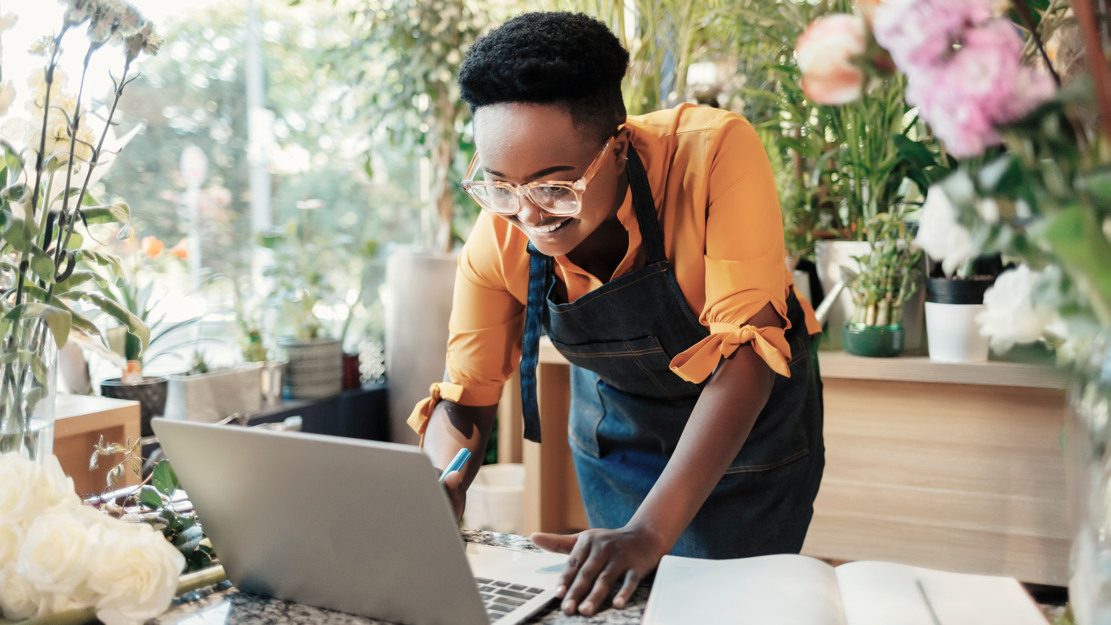 Image of Black woman leaning over laptop