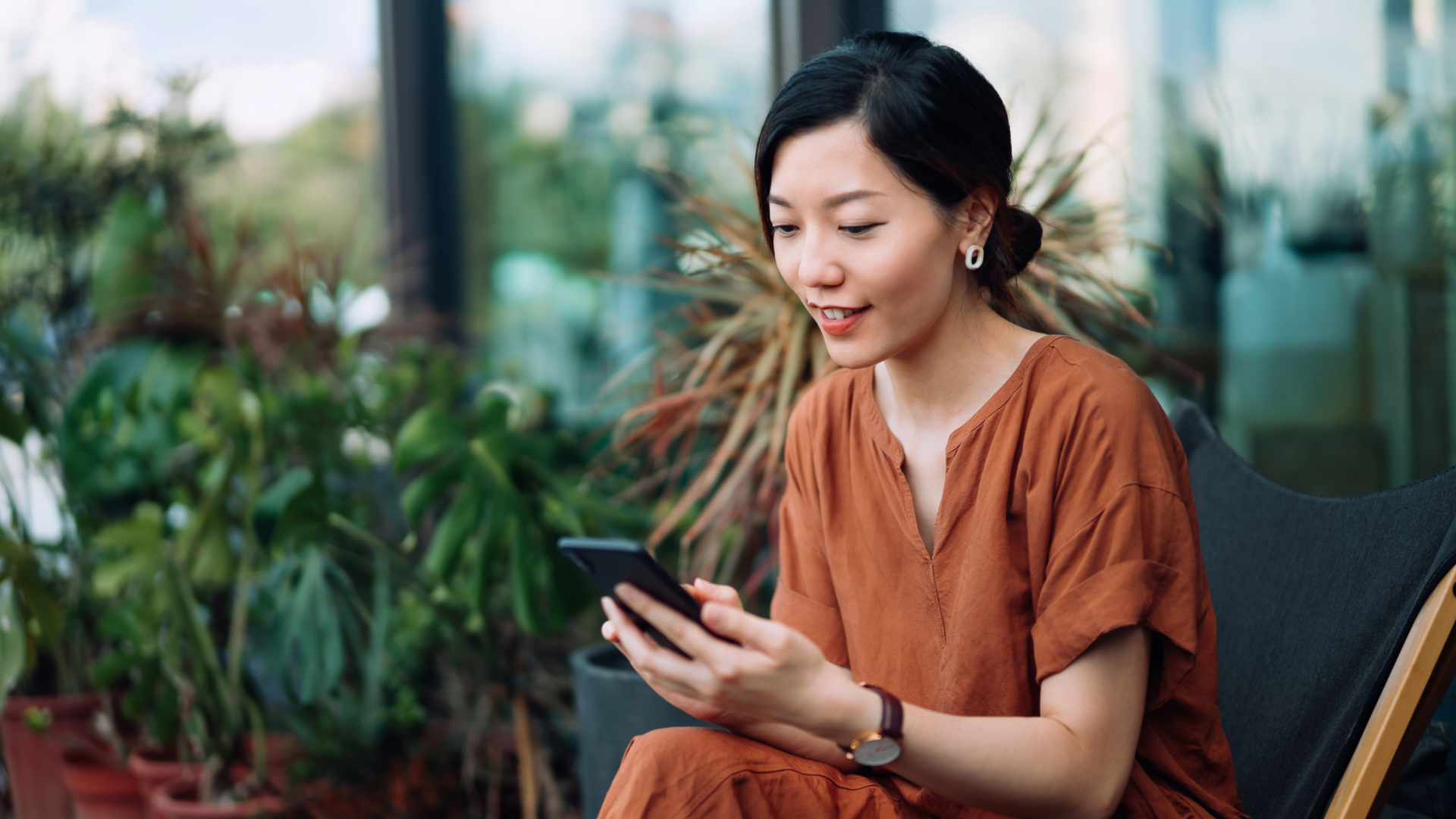A woman smiling and looking at her cell phone.