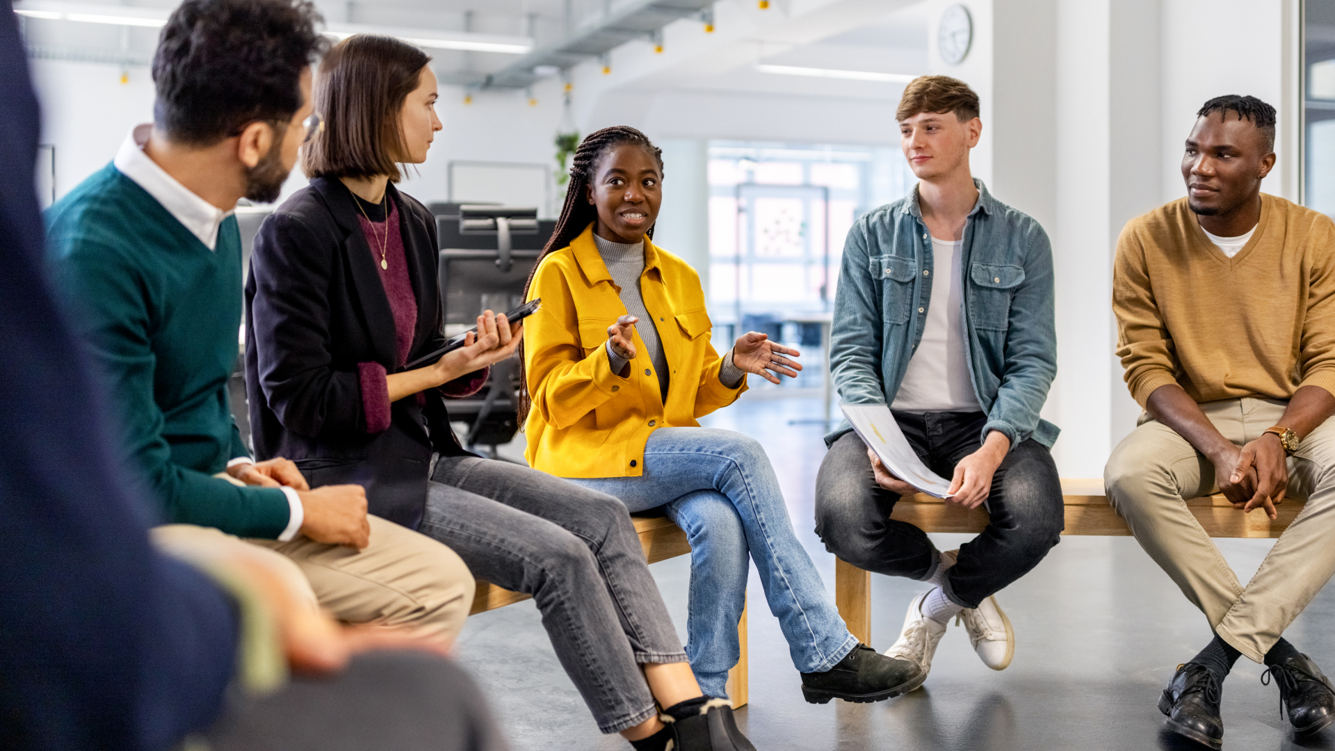 A group of people sitting in a semicircle and talking with one another.
