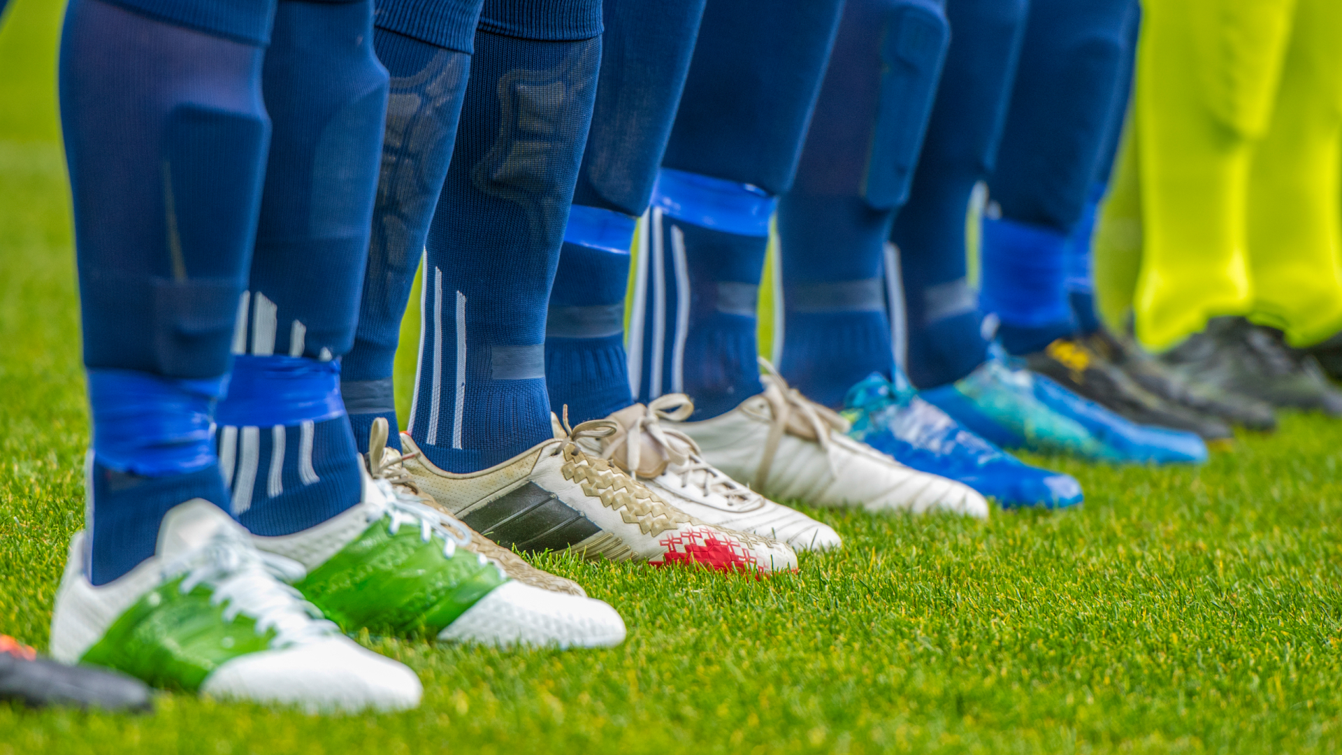 An image showing the cleats of multiple soccer players on a pitch.