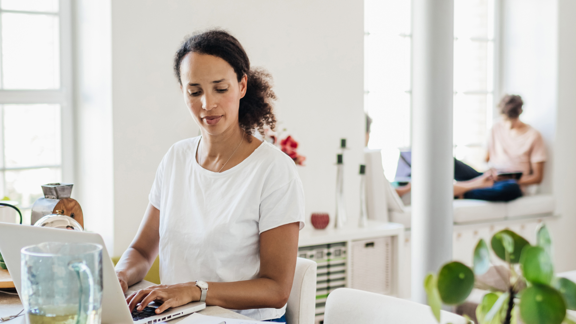 Image showing a parent on her computer, as children use their devices in the background.