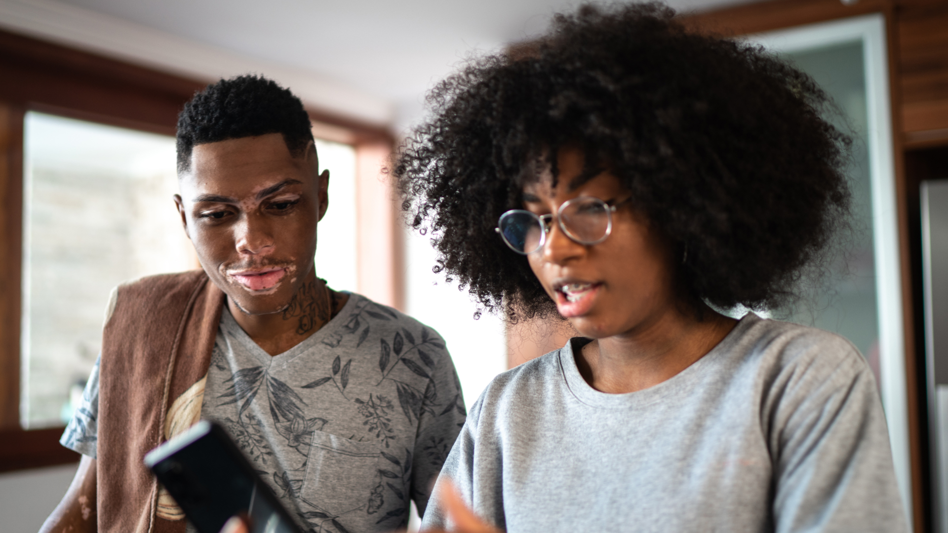 An image of two teens looking at a cell phone.