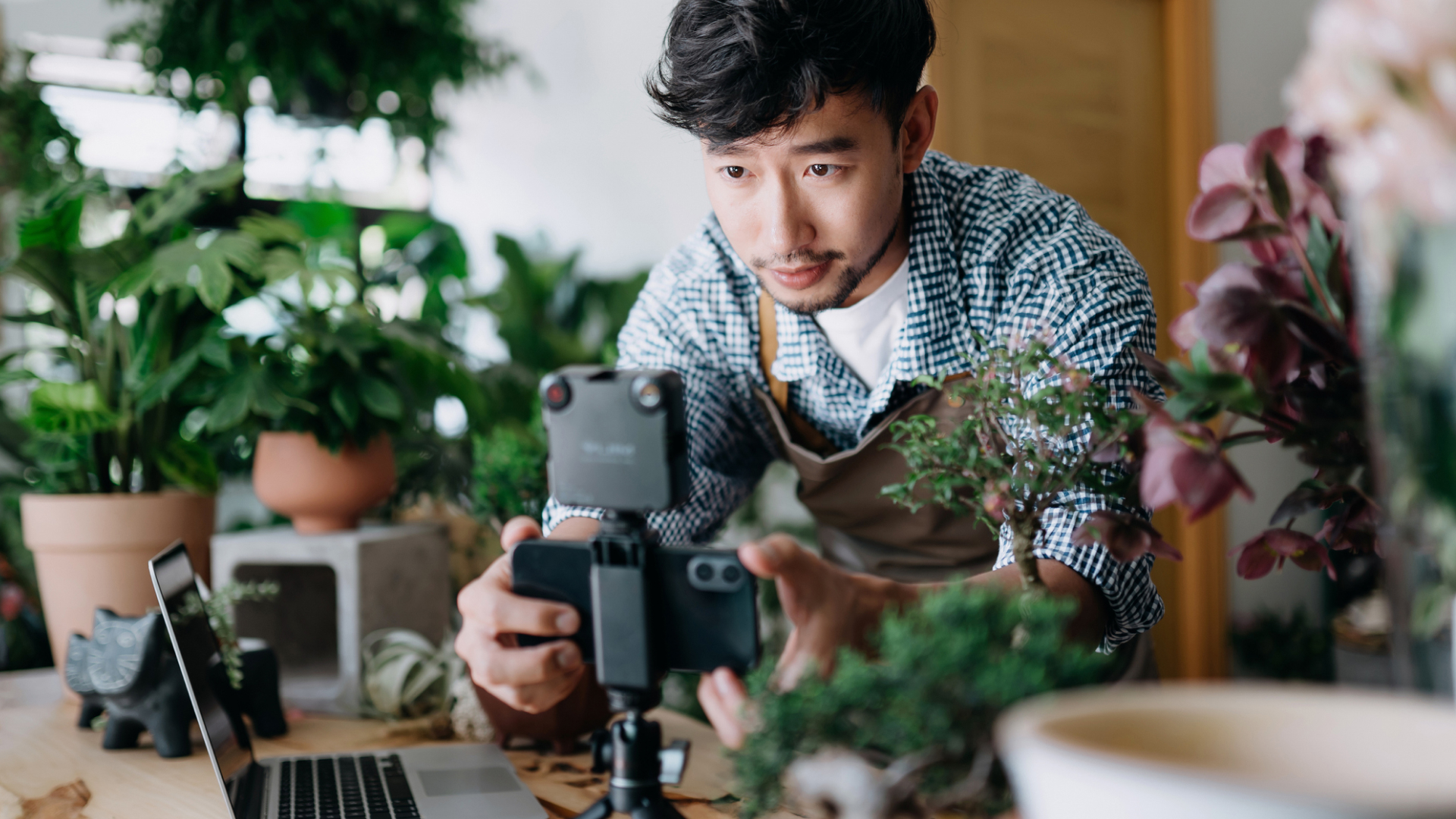 Man surrounded by plants filming on tripod